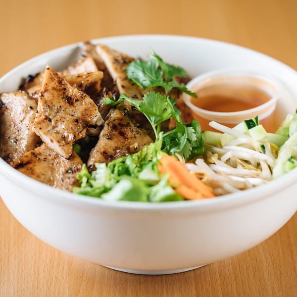 Pho Crimson's grilled chicken vermicelli bowl with fresh vegetables and a side of sauce.